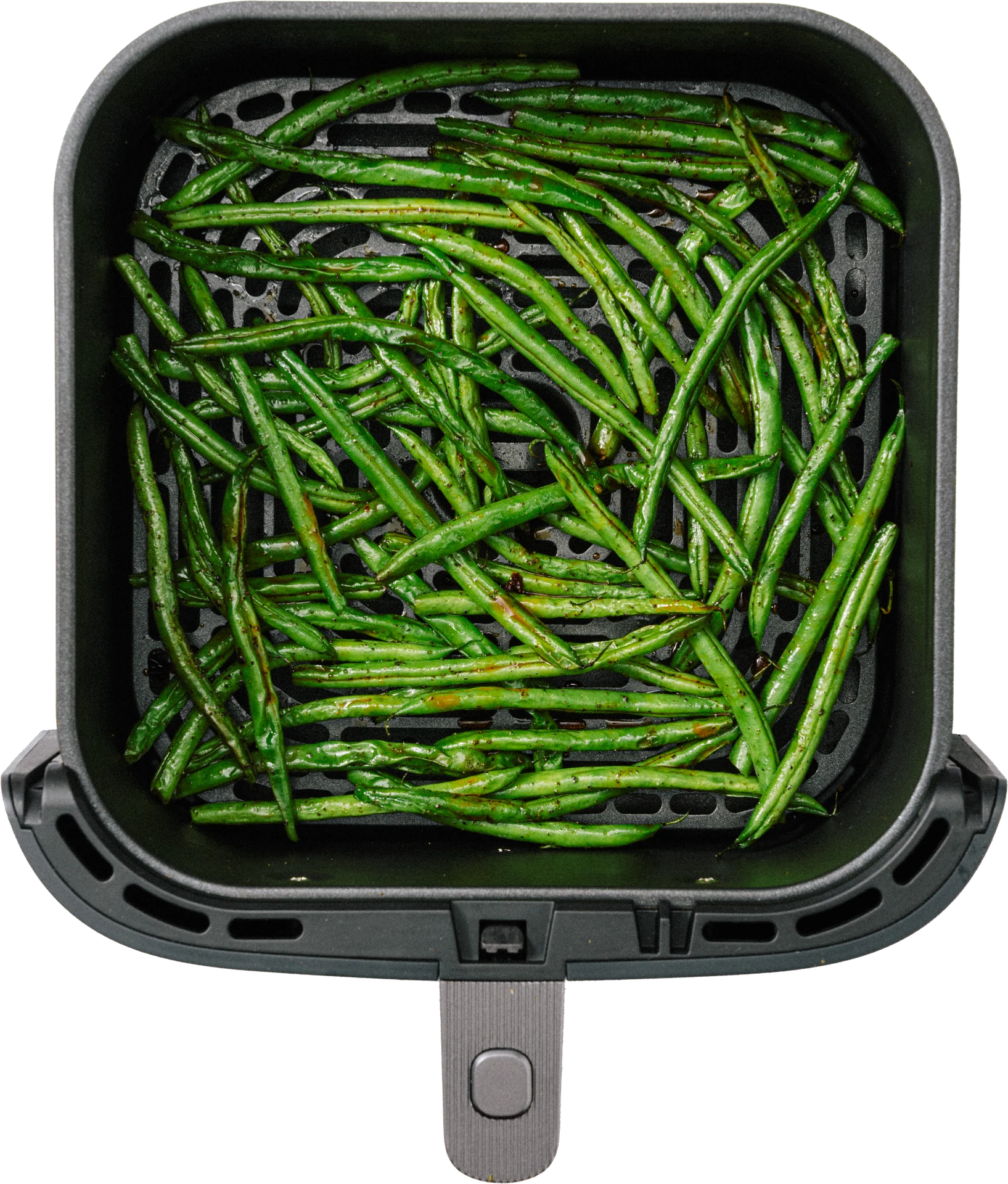 A black air fryer basket filled with cooked green beans, arranged neatly.